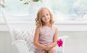 menina sentada em cadeira com rosa na mao